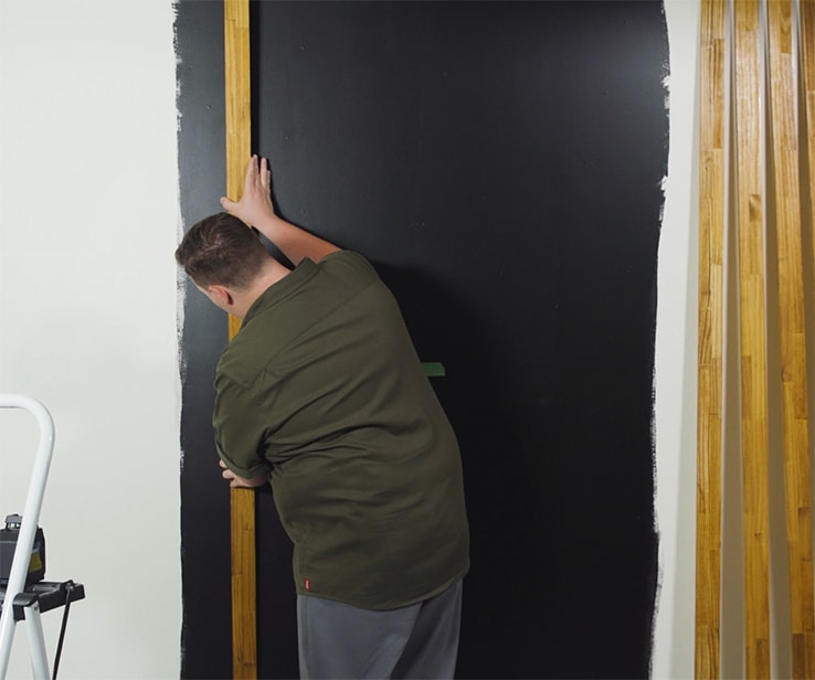 Homme collant des lattes de bois sur un mur