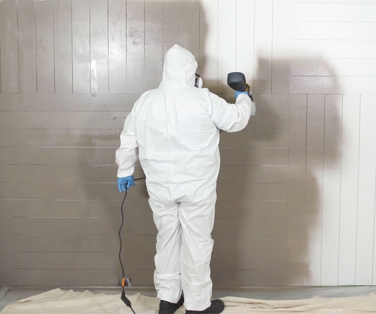 Homme utilisant un pistolet à peinture pour peindre un mur