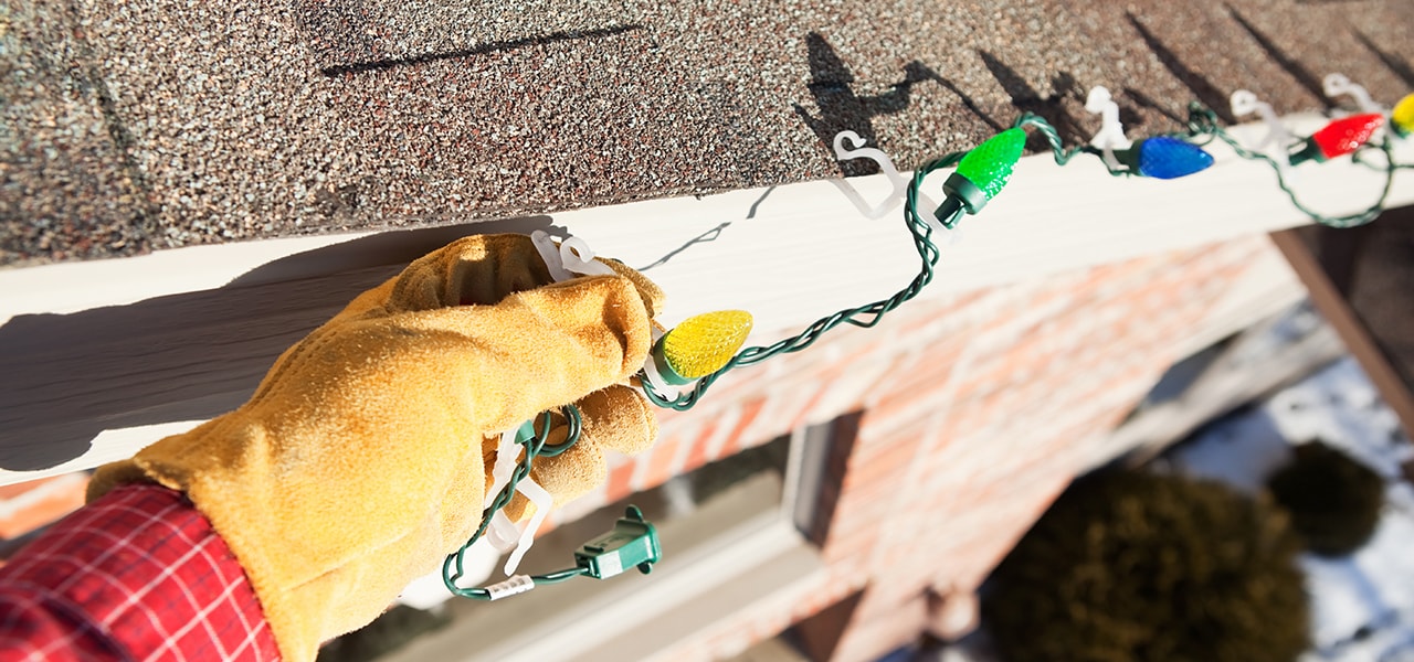 Personne accrochant des lumières sur une toiture