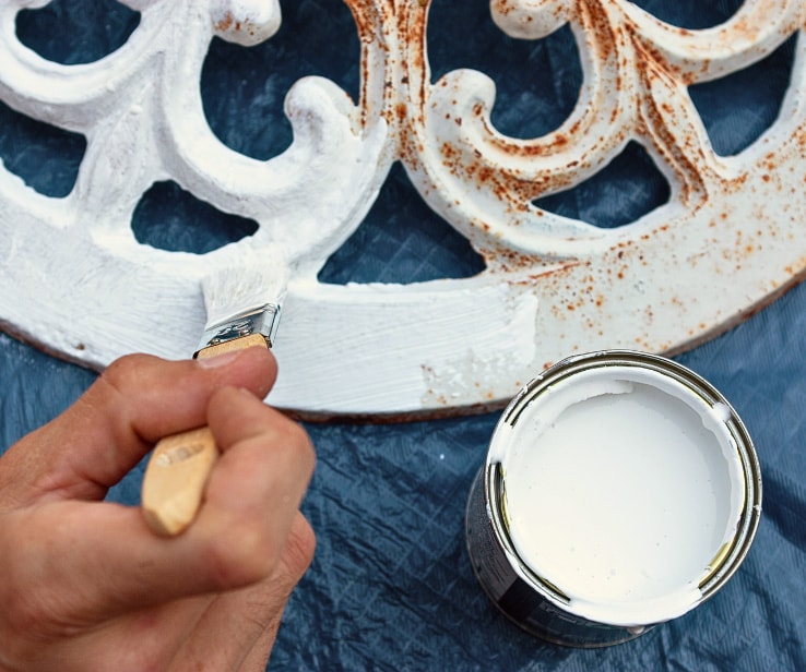 Person painting a cast-iron umbrella support