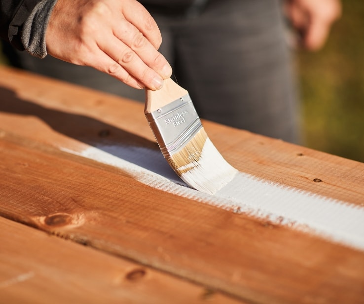 Person painting treated wood planks