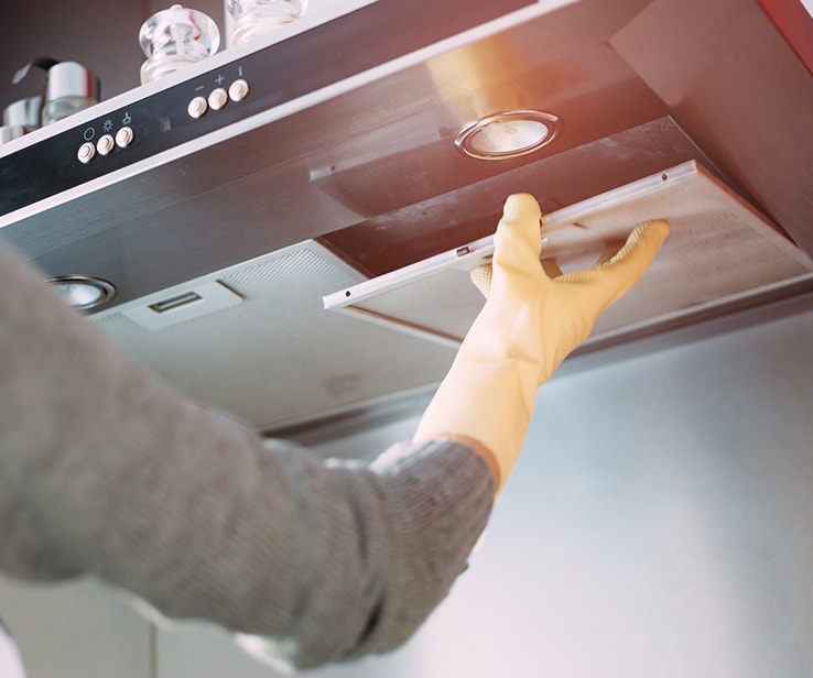 Person cleaning a kitchen range hood