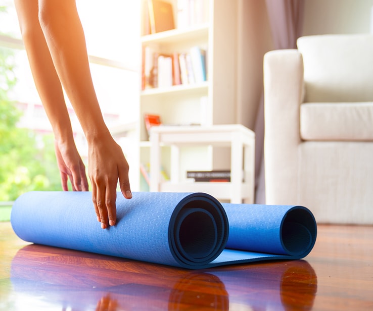 Femme roulant un tapis de yoga