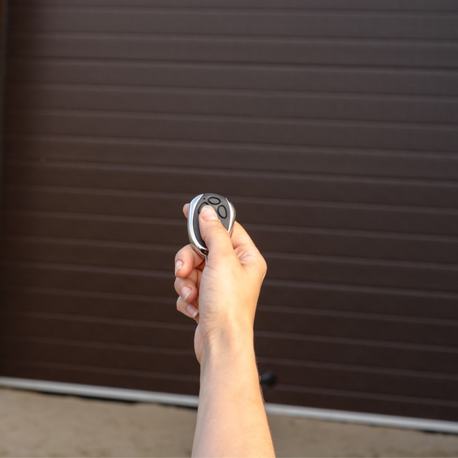 Personne qui ouvre une porte de garage avec une télécommande