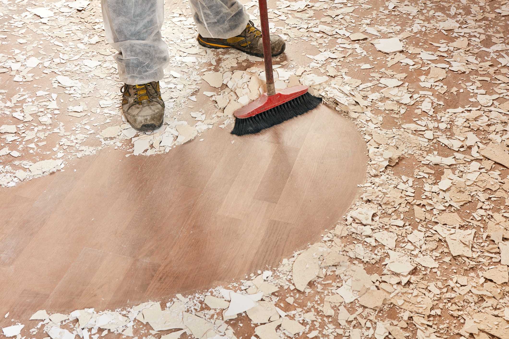 Person cleaning a floor covered in building supplies