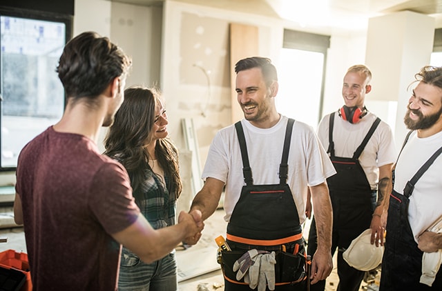 Couple shaking hands with three contractors