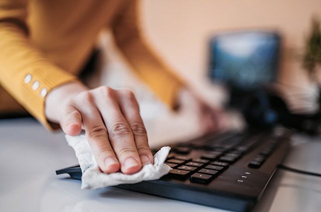 Personne nettoyant un clavier d’ordinateur