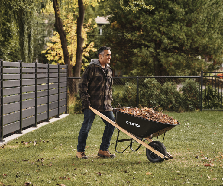 Man using a wheelbarrow in a backyard