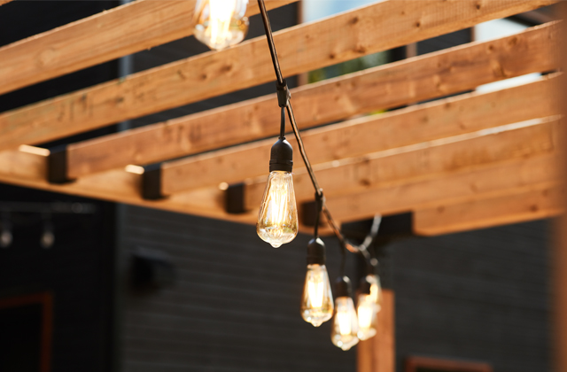 Guirlande lumineuse accrochée sur une pergola en bois