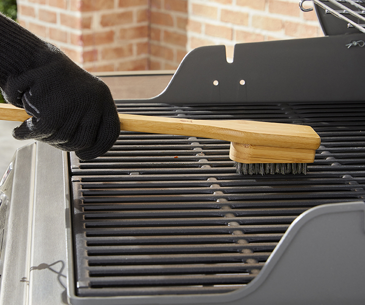 Person cleaning a barbecue with a brush