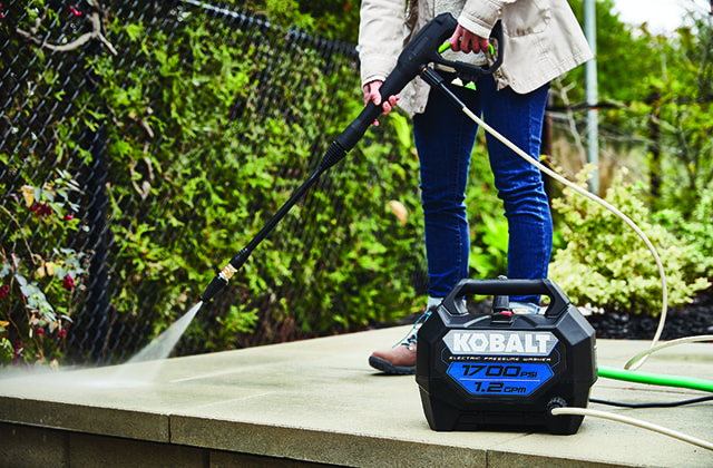 Woman cleaning a patio with a pressure washer